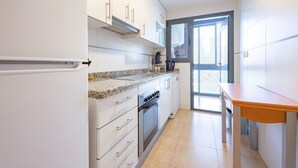 A modern kitchen with white cabinetry, a built-in oven, and a granite countertop.