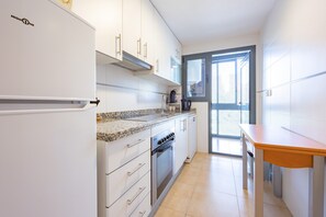 Eine moderne Küche mit weißen Schränken, einem eingebauten Backofen und einer Arbeitsplatte aus Granit.