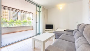 A living room with a sofa, a white coffee table, and a TV on a stand.