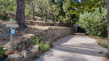 A gravel path leading to a stone wall with a sign indicating 'ESSENCIA' and a parking sign.