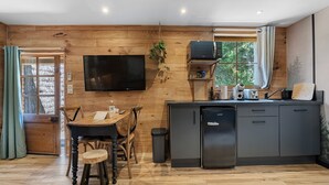 Una cocina moderna con pared de madera, un televisor de pantalla plana, un refrigerador y un comedor con mesa y sillas de madera.