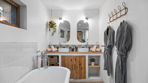 Un baño moderno con bañera, tocador de madera, dos espejos y un perchero para bata.