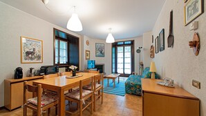 Een gezellige woonkamer met een eethoek, een open haard en een groot raam.