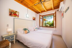 Un dormitorio con dos camas, techo de madera, ventana con vistas y aire acondicionado instalado en la pared.