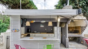 A modern outdoor kitchen with a bar area, two chairs, and a grill.