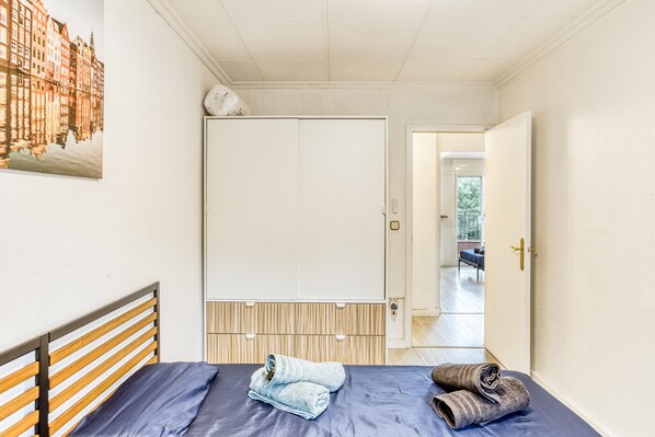 A bedroom with a bed, a wardrobe, and a view of a building through a window.