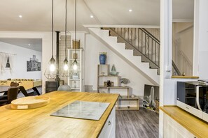 A modern kitchen with a wooden island, pendant lights, and a staircase leading to a loft.