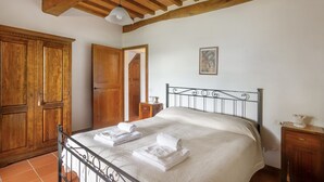 A bedroom with a bed, wooden wardrobe, and a small bedside table.