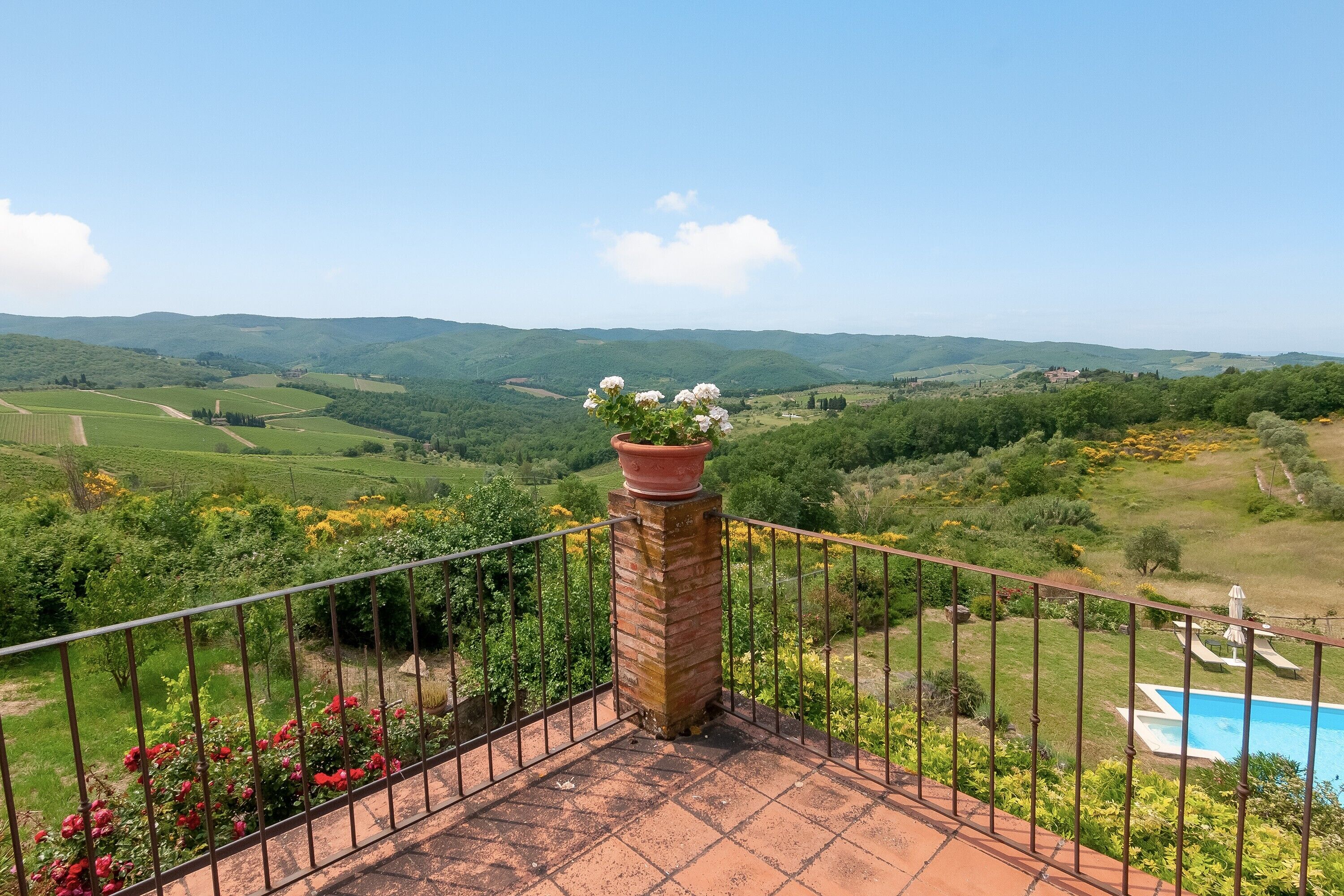 Eine Terrasse mit Blick auf sanfte Hügel, einem Ziegelkamin und einem Blumentopf.