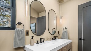 A modern bathroom with a double sink, two mirrors, and a towel rack.