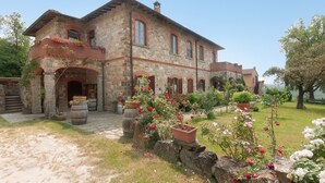 A stone building with arched windows and a balcony with flowers. - Apartment 'Il Magnifico' with Shared Pool, Private Terrace and Wi-Fi (Unknown)