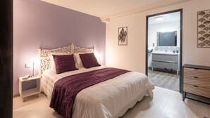 Une chambre à coucher comprenant un lit, une table de chevet et une porte donnant accès à une salle de bain.