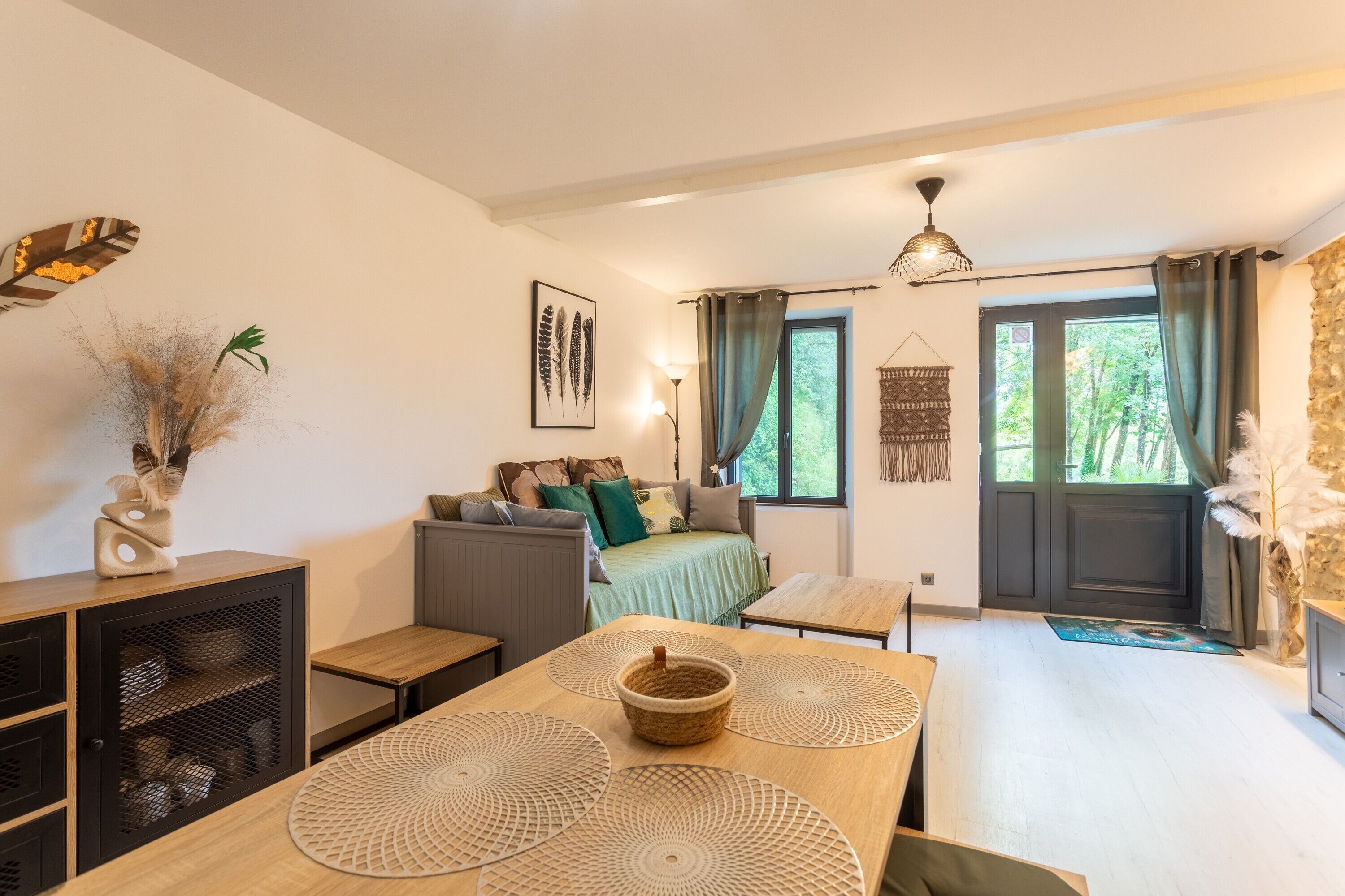 A cozy living room with a sofa, a dining table with placemats, a decorative basket, and a bookshelf.