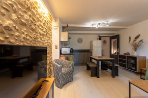 Una cocina moderna con pared de piedra, una zona de comedor con banco y una mesita.
