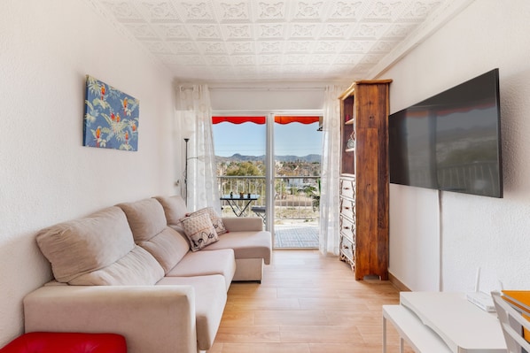 Un salon avec un canapé, un téléviseur et un balcon offrant une vue agréable.