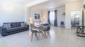 Un salon moderne avec un canapé, une table à manger, des chaises et un tableau accroché au mur.