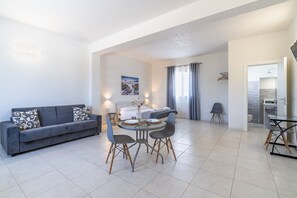 A modern living room with a sofa, dining table, chairs, and a painting on the wall.