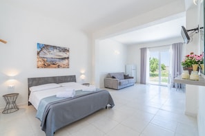 Un dormitorio moderno con cama, mesitas de noche, un sofá y vistas al exterior.