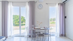 Una habitación con una mesa de comedor, sillas, un reloj y vistas a través de un ventanal.