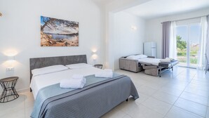 Una habitación de hotel moderna con una cama grande, otra más pequeña, un escritorio, una silla y un cuadro con una playa.