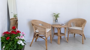 Un rincón con dos sillones de mimbre, una mesita y una planta en maceta.