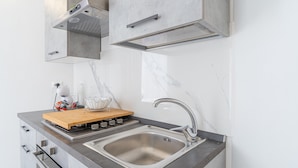Una cocina moderna con pileta de acero inoxidable, tabla de cortar de madera y electrodomésticos integrados.