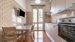 Une cuisine équipée d’un téléviseur, une table à manger avec des chaises, et une vue à travers la porte.