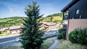 Un edificio con fachada oscura, un balcón visible y vistas a un paisaje verde con casas.