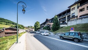 Una calle con coches estacionados, un cartel de prohibido estacionar y edificios con balcones.
