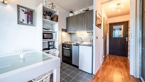 Una cocina compacta con una mesa de comedor, horno empotrado y refrigerador.