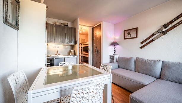 Un espacio habitable compacto con una mesa de comedor, sillas, sofá, zona de cocina y cama.
