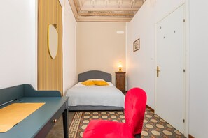 Une chambre à coucher avec un lit, une chaise rouge, une table de chevet, un miroir et une porte.