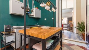 A kitchen with a wooden table, hanging mugs, a microwave, and a sink. - Room 'Ds - Camera Tripla' with Shared Terrace, Wi-Fi and Air Conditioning (Catania)