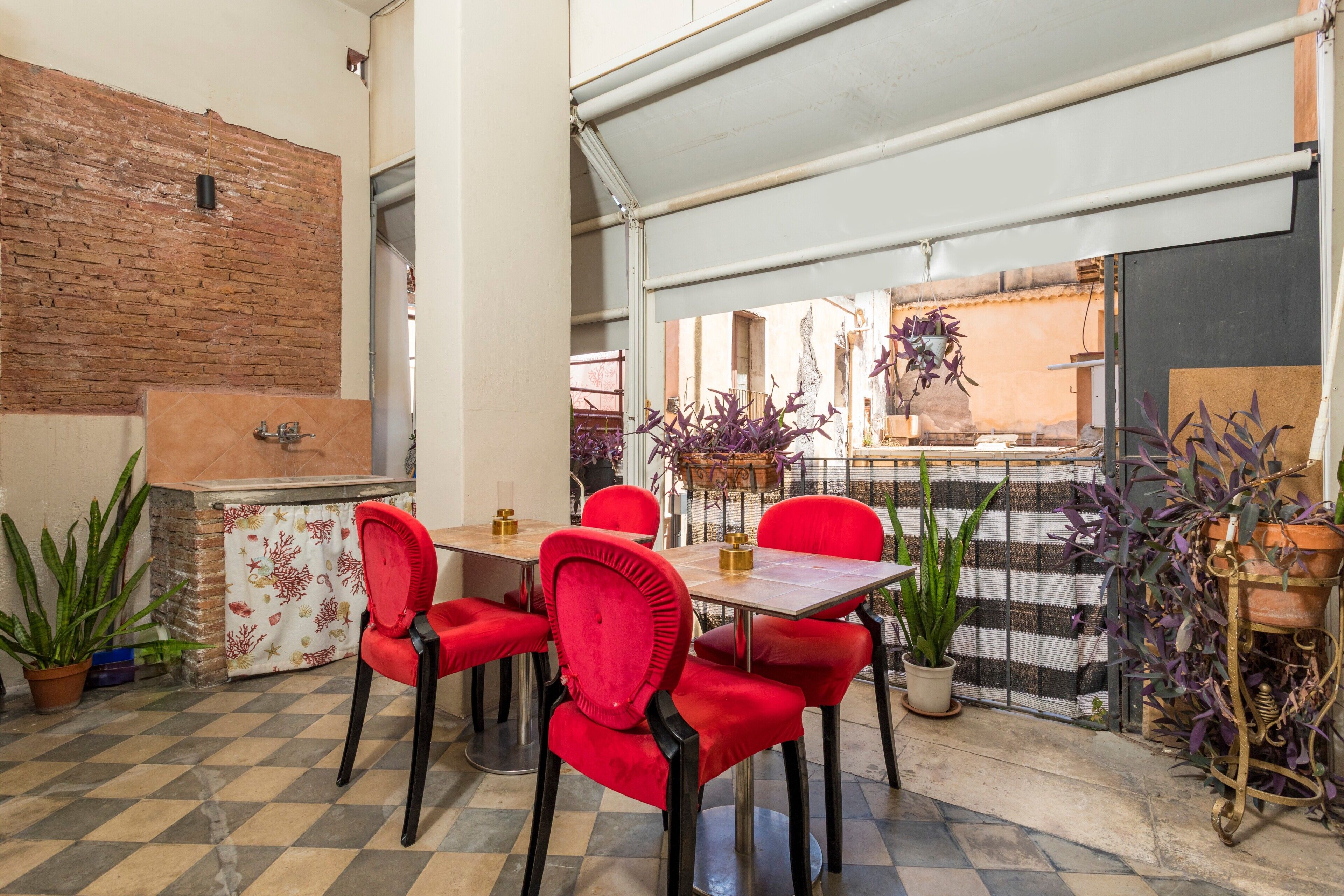 A dining area with red chairs, a table, and a brick wall.