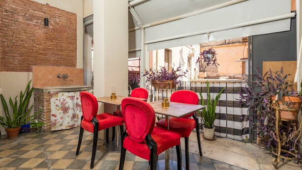 A dining area with red chairs, a table, and a brick wall. - Room 'Ds - Camera Tripla' with Shared Terrace, Wi-Fi and Air Conditioning (Catania)