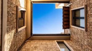 A narrow corridor with a skylight leading to a clear blue sky.