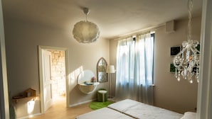 A bedroom with two beds, a green rug, a hanging light fixture, and a window with curtains. - Holiday Home 'Appartamento in Villa Umbriace' with Shared Pool, Wi-Fi and Air Conditioning (Stroncone)