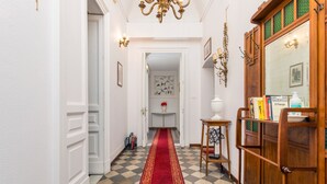 A hallway with a checkered floor, a red carpet, a wooden cabinet, and a mirror.