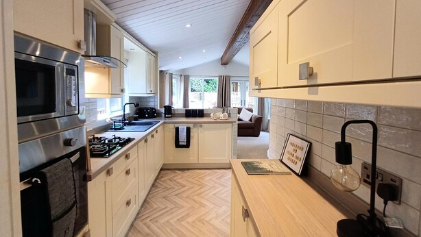Une cuisine moderne dotée d’appareils électroménagers en acier inoxydable, de meubles de rangement en bois et d’un parquet disposé en motif à chevrons.