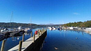Un port de plaisance avec des bateaux amarrés le long de quais en bois, une eau calme et un ciel bleu dégagé.