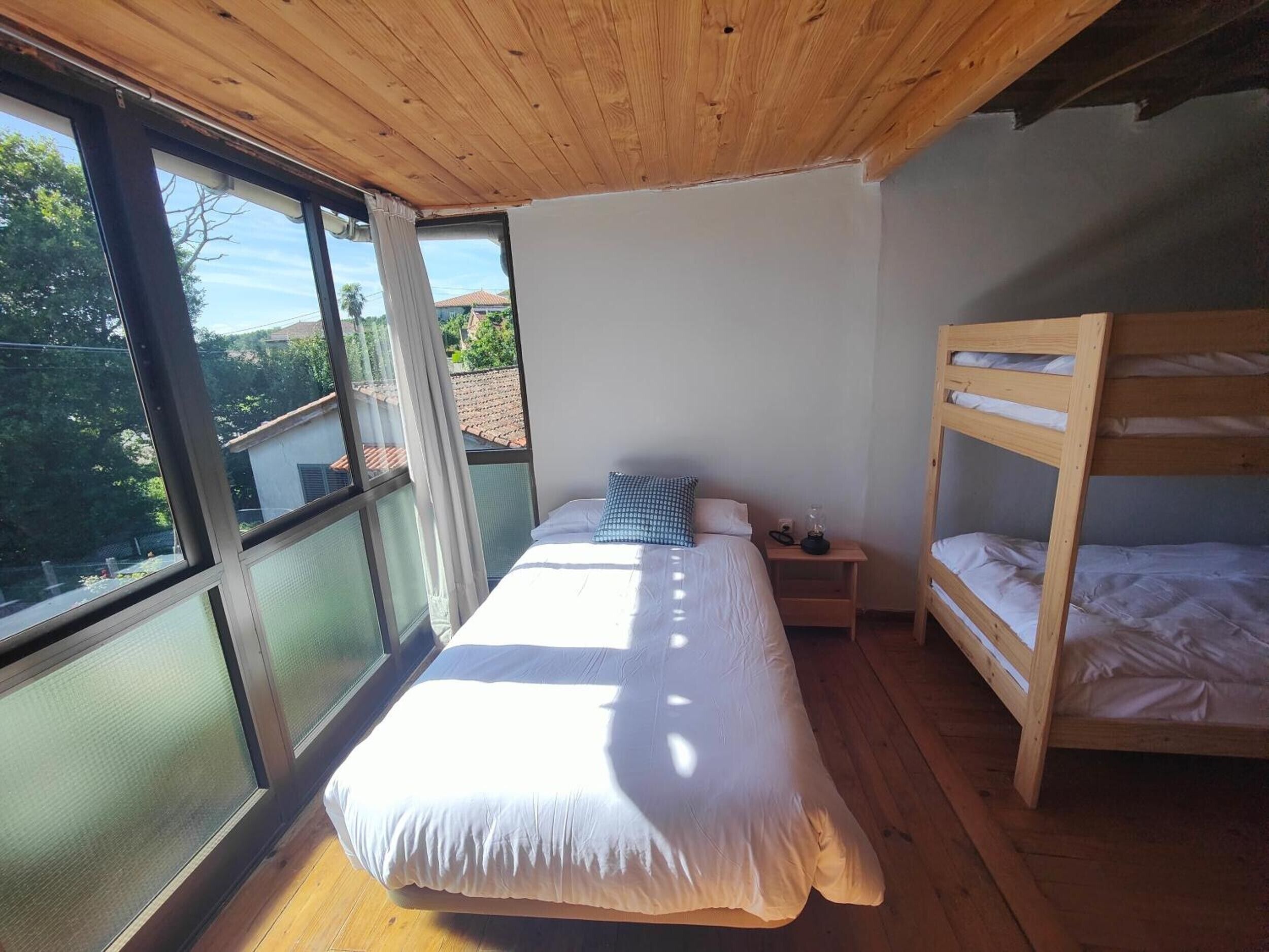 Quarto com uma janela grande, uma cama beliche e uma mesa de cabeceira.