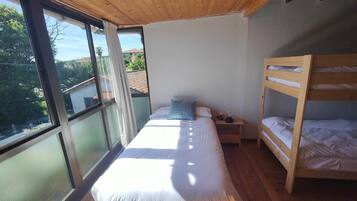 Quarto com uma janela grande, uma cama beliche e uma mesa de cabeceira.