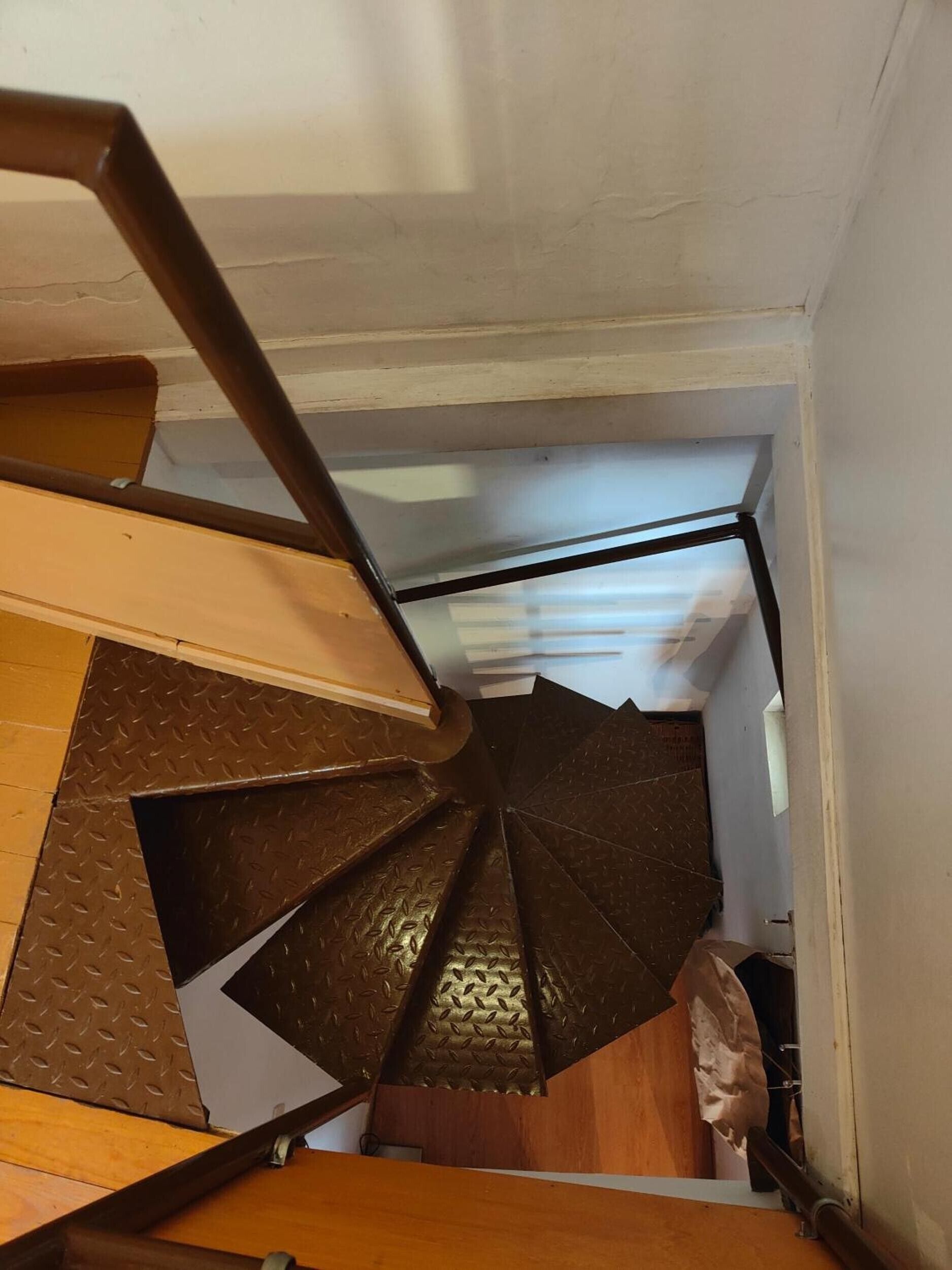 Un escalier en colimaçon avec une rampe métallique et des marches en bois.