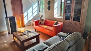 Una sala de estar con sofá, mueble, mesa de centro y chimenea.