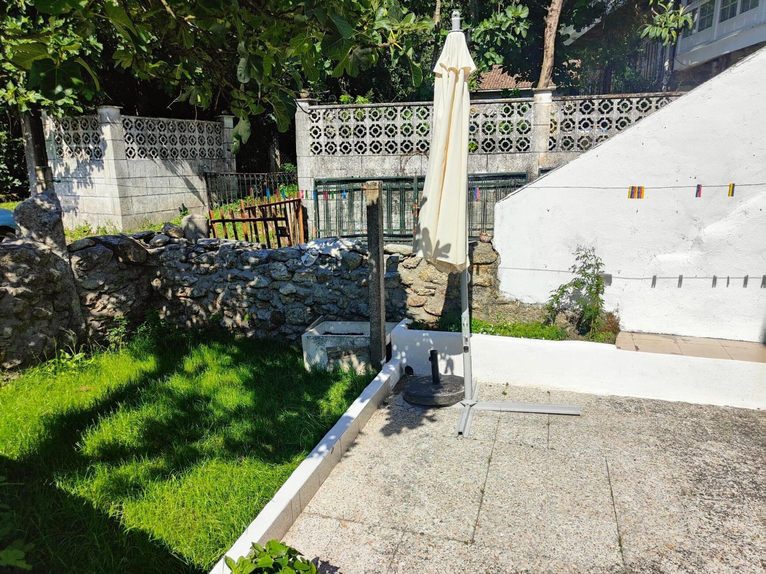 A stone wall, a white fence with decorative patterns, and a grassy area.