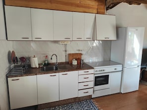 A kitchen with white cabinets, a stainless steel sink, a stove, and a refrigerator.