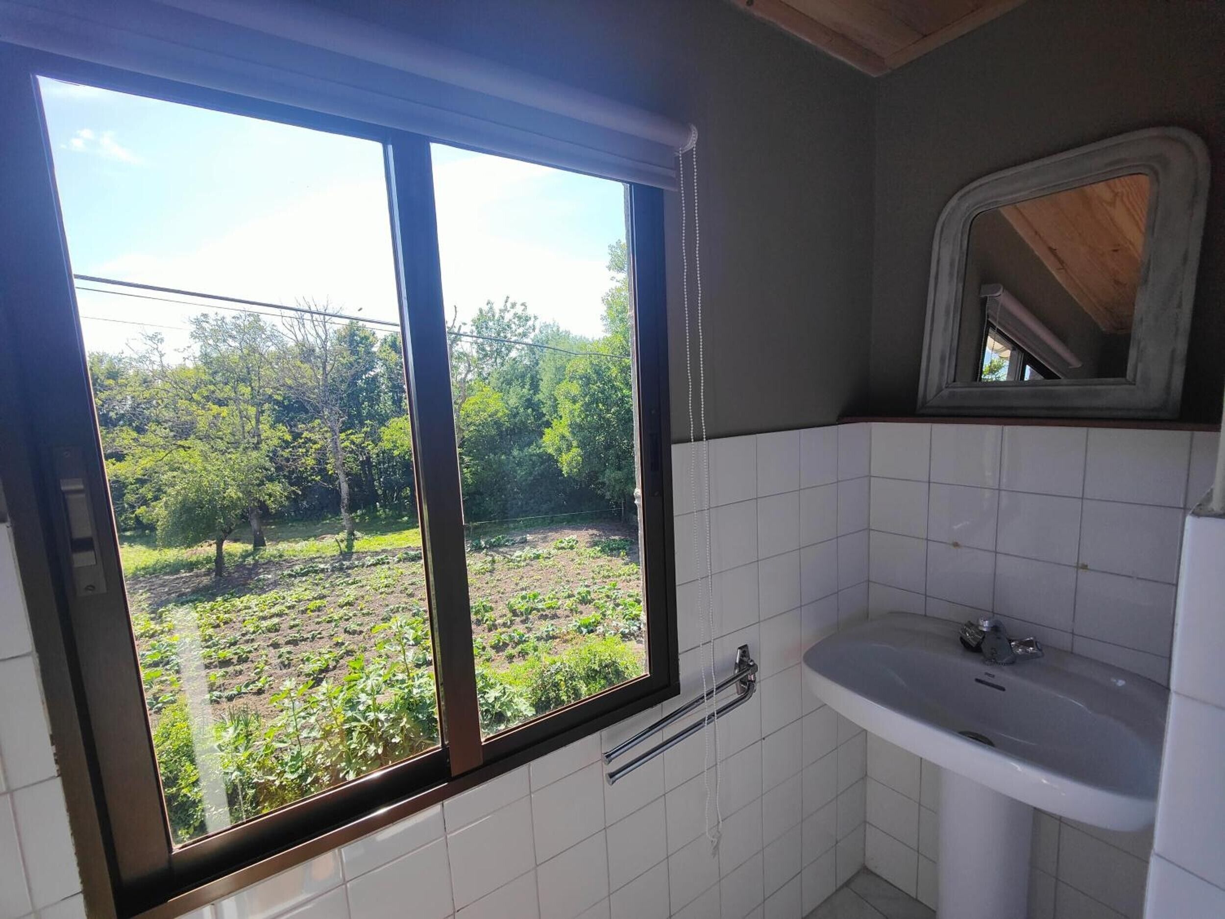 Ein Badezimmer mit Fenster, Waschbecken und Spiegel.