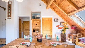 Un comedor con una mesa de madera, sillas y vistas al cielo a través de un tragaluz.
