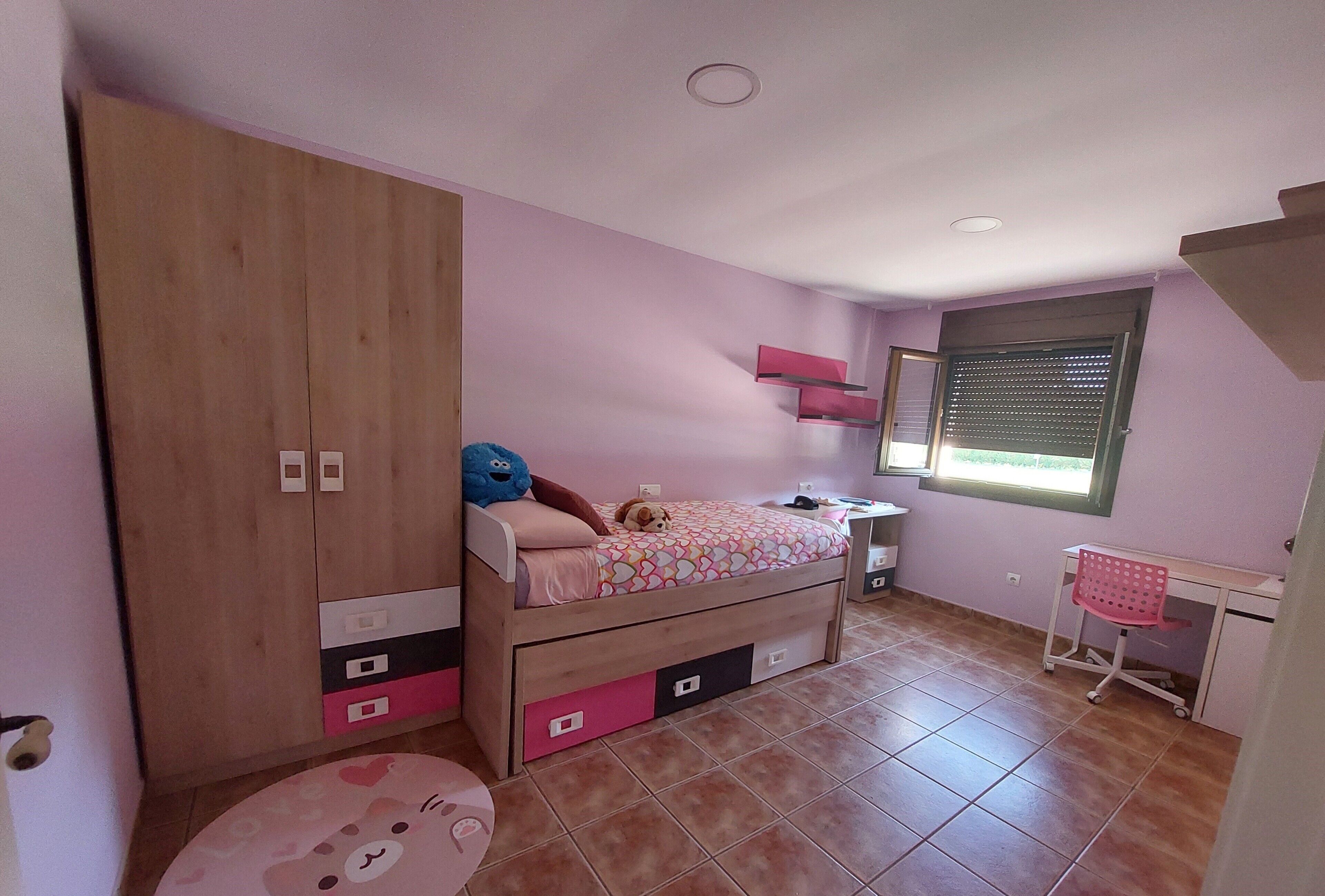Un dormitorio con cama, armario, escritorio y ventana.