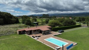 Une maison avec une piscine, un jardin clos et une vue sur la campagne environnante.